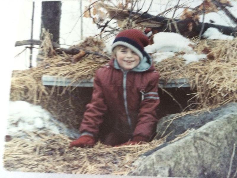 A scrappy 10-year-old Erica Hargreave in a toque and snowsuit crawling out of a snow tunnel